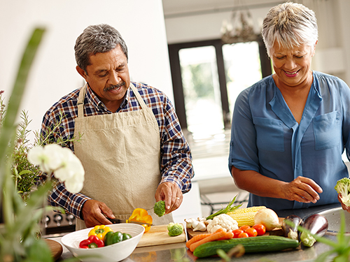 Couple trying a new recipe in the kitchen for a community dinner>